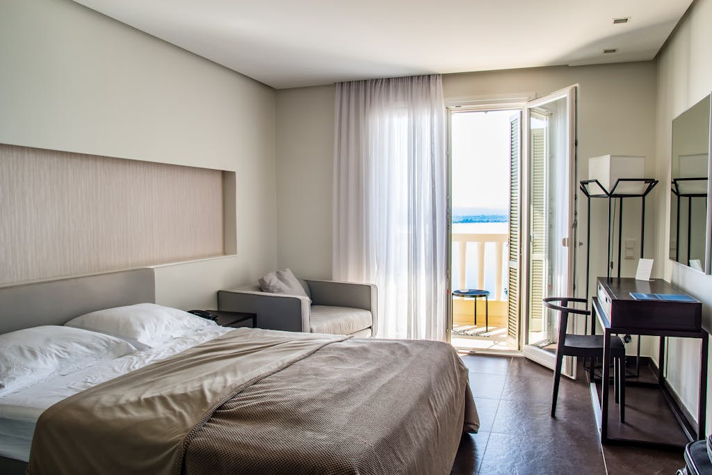 Spacious, elegantly furnished hotel room featuring a balcony with a sea view and modern amenities.