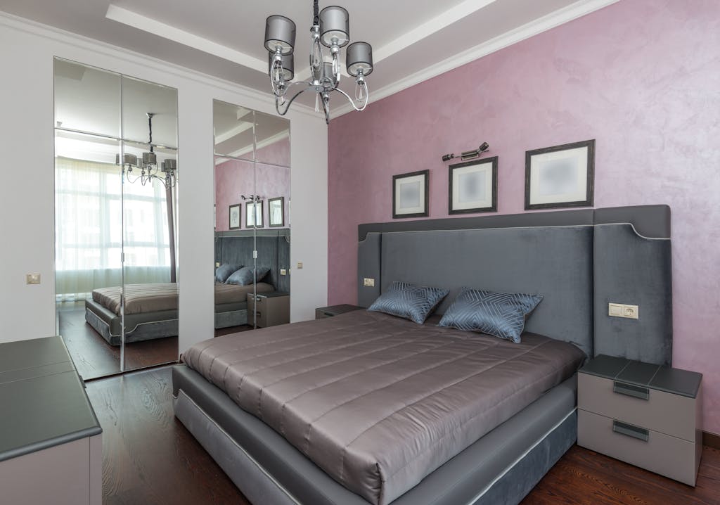 Stylish hotel bedroom featuring a luxurious bed, mirrored wardrobe, and lilac walls.